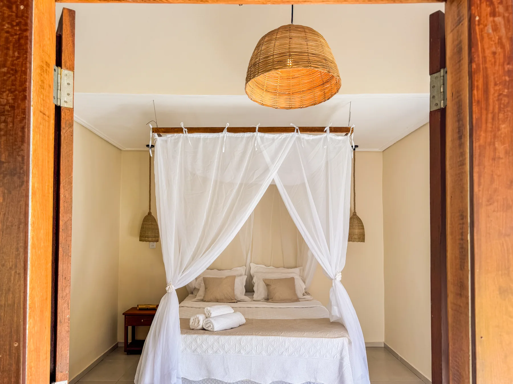 Quarto da Casinha Independente da NAK com cama de casal, dossel em tecido e decoração em madeira natural.