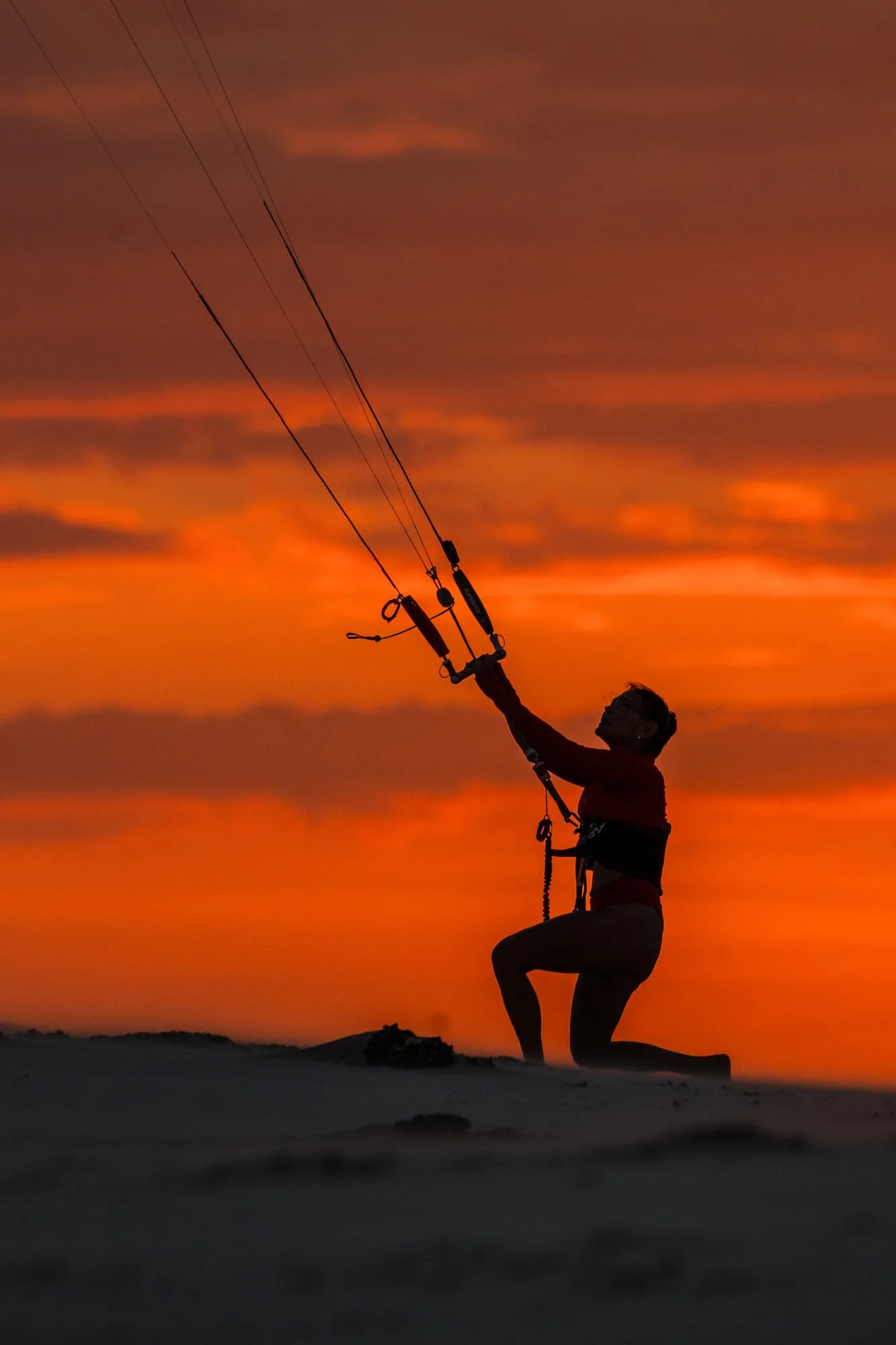 Kitesurfista preparando o equipamento sobre as dunas durante o pôr do sol nos Lençóis Maranhenses.